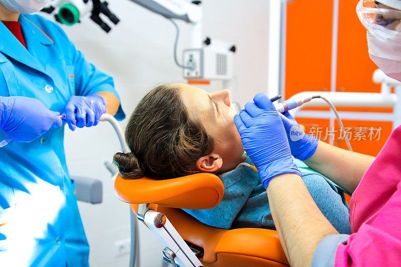 牙医和他的助手在牙科诊所治疗patientâ的牙齿。